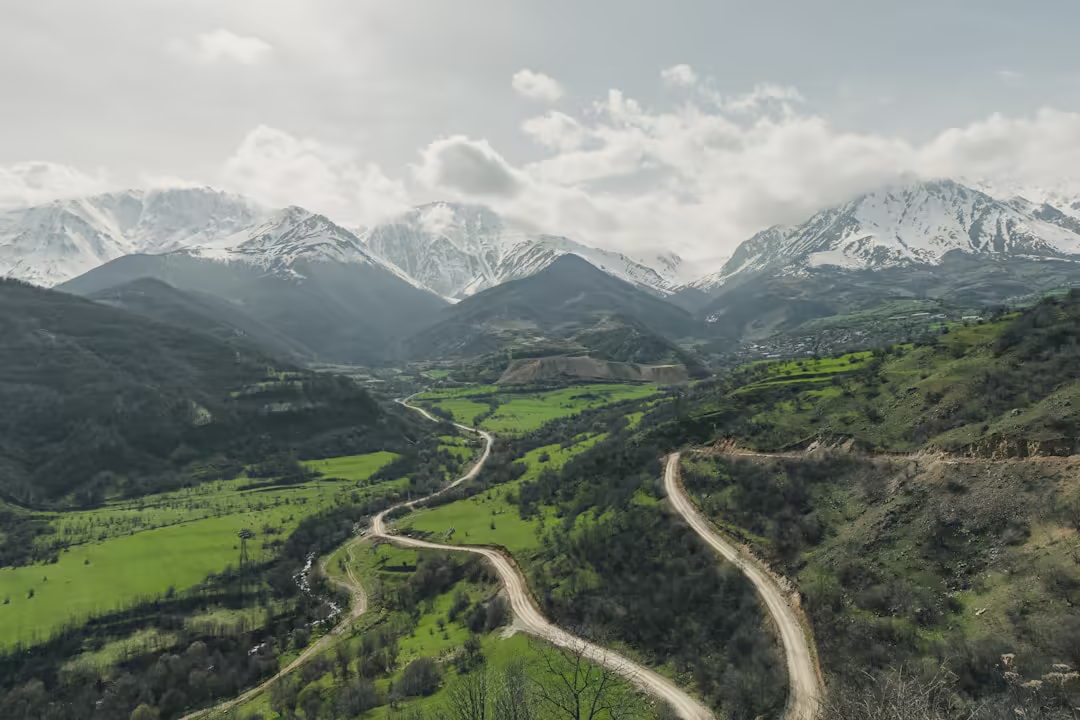 A winding road through a green Armenian valley beneath snow-capped mountains